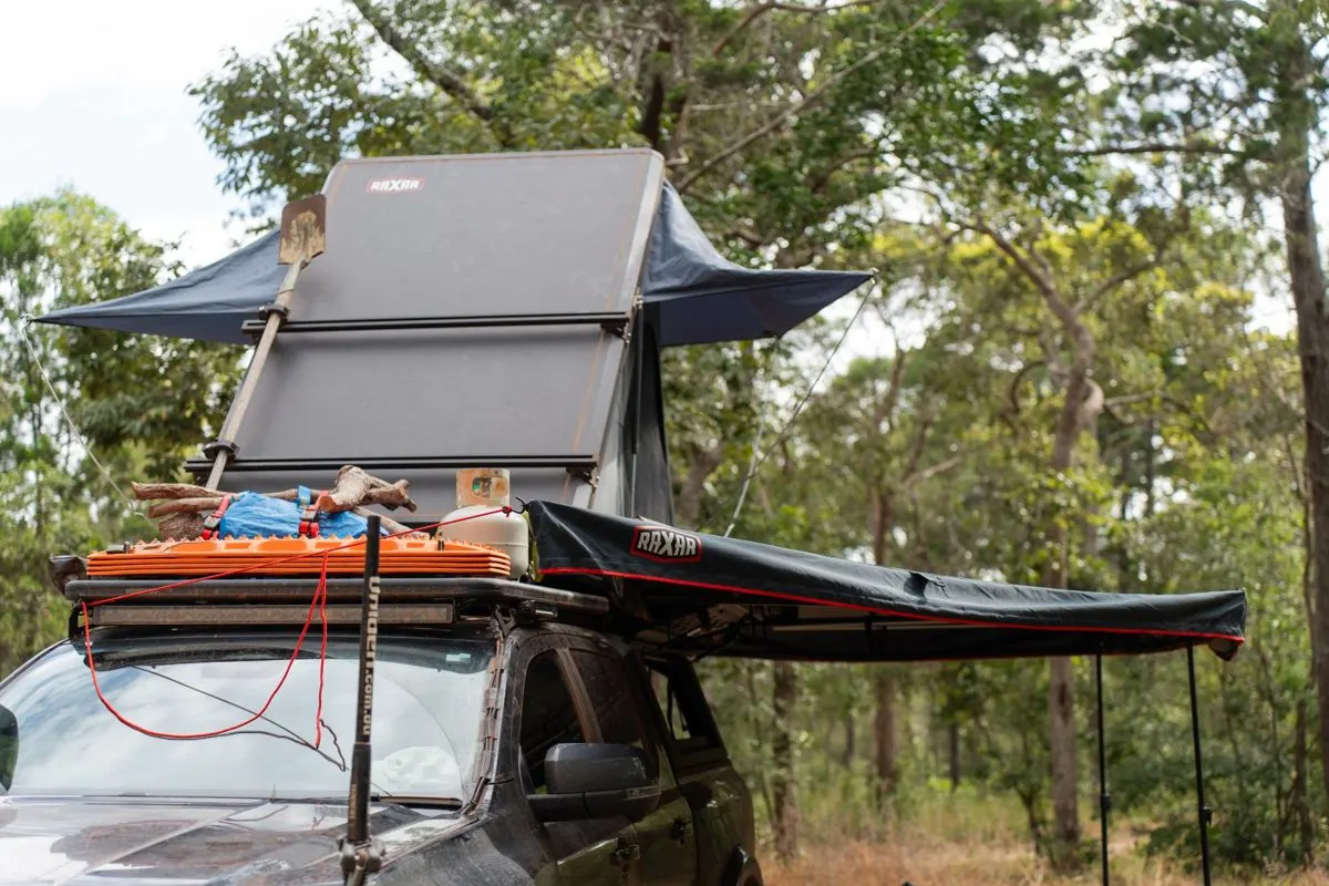 Ute with a rooftop tent and awning set up at a bush camp