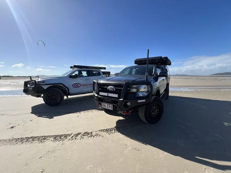 Two Ford Rangers with Opposite Lock bull bars and all terrain tyres on a beach